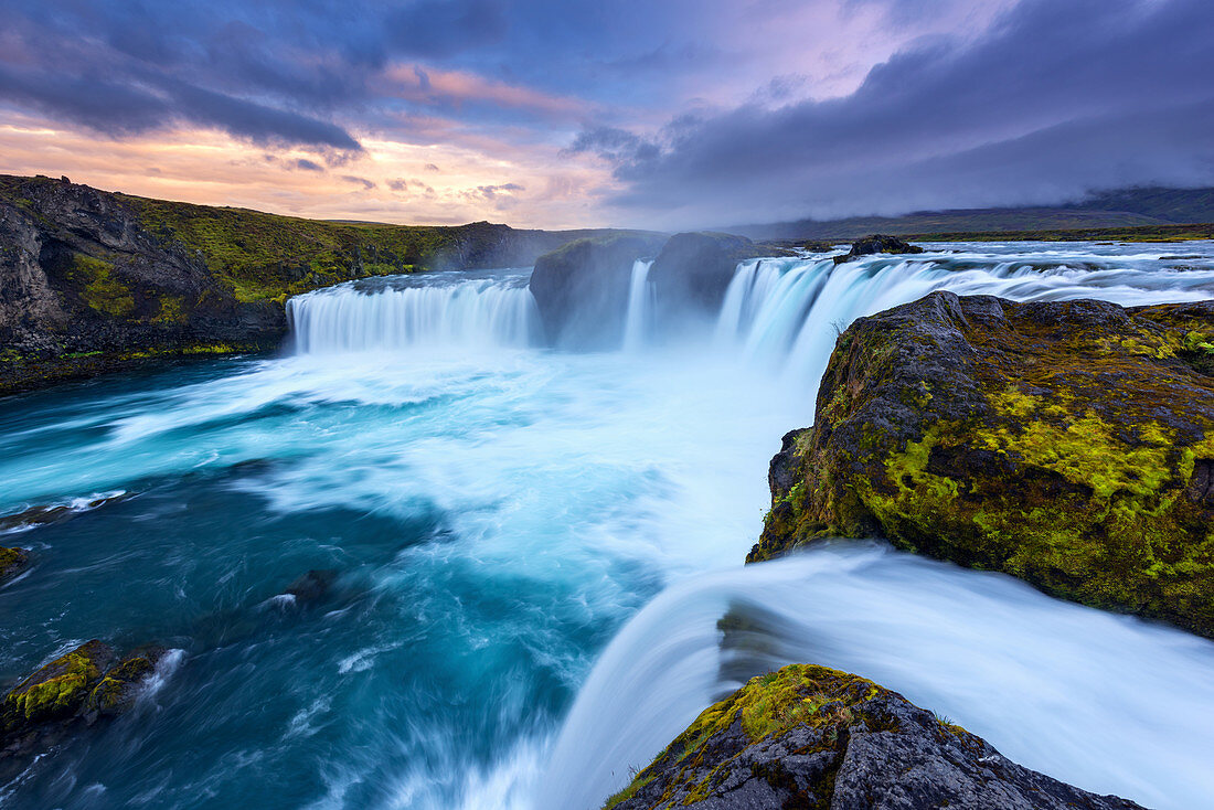 Godafoss waterfall with glowing turquoise and white spray at sunset in Iceland, Europe