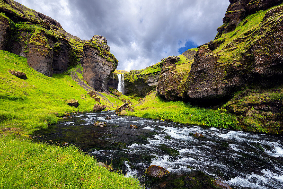 Rocky landscape around Kvernufoss waterfall with river in foreground: Iceland, Europe