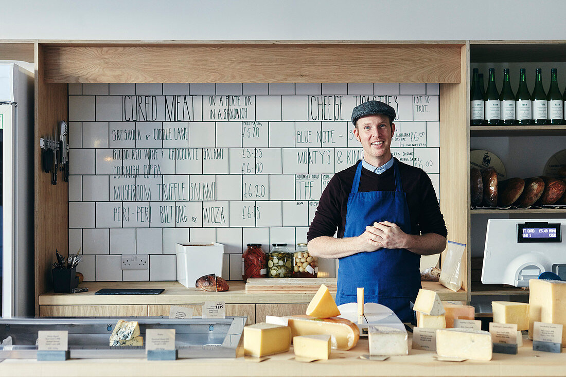 Porträt des Käsehändlers mit einer Vielzahl von Käsesorten
