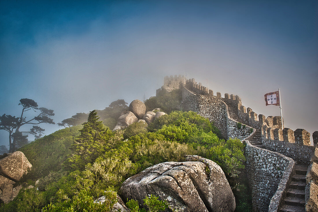 Wall and fortified tower in the raging fog in Castelo dos Mouros Sintra, Lisbon, Portugal