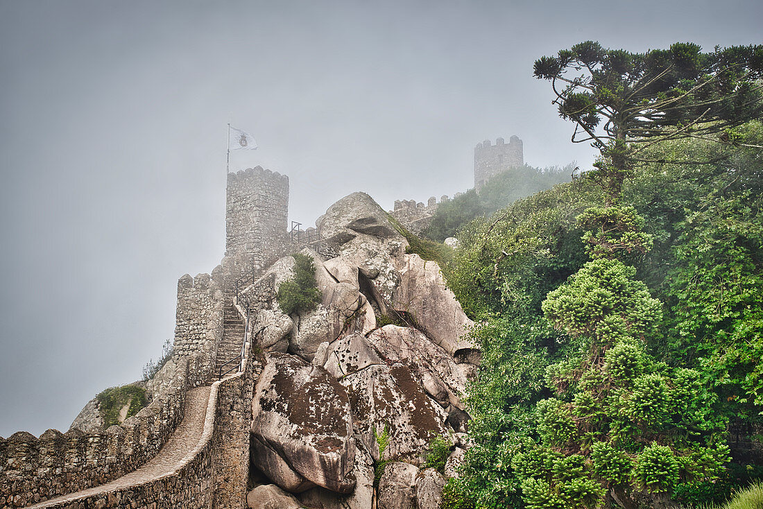 Wall and fortified tower in the fog in Castelo dos Mouros Sintra, Lisbon, Portugal