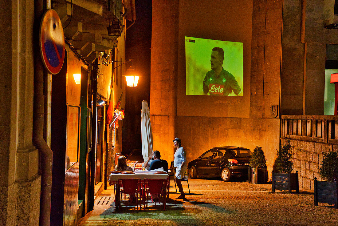 Bar in einer Gasse mit Projektion eines Fussbalspiels auf eine Hauswand, Guimarães, Minho, Nordportugal, Portugal