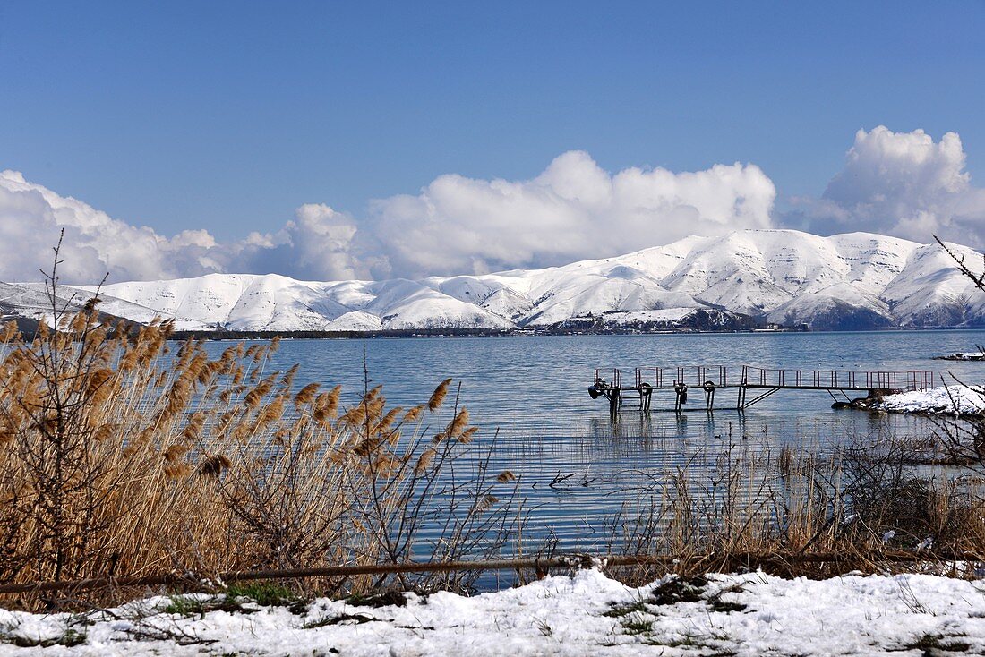 Steg am Ufer des Sees, Blick von der Halbinsel Sewan mit schneebedeckten Bergen, Sewansee, Armenien, Asien