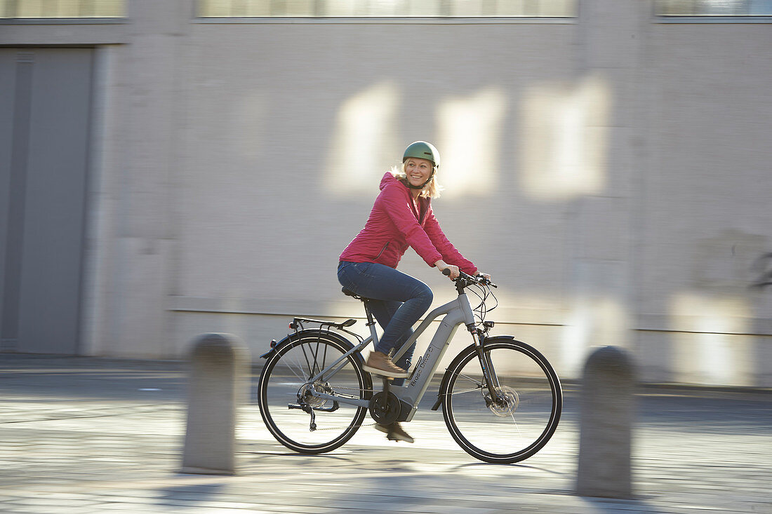 Junge Frau auf Fahrrad in urbaner Umgebung, München, Bayern, Deutschland