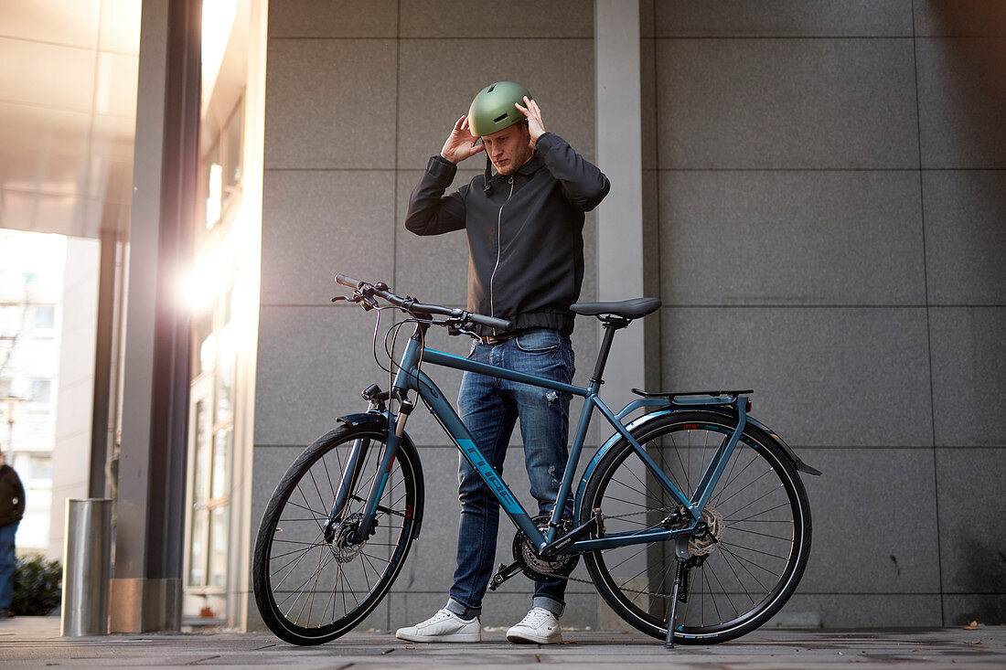 Junger Mann mit Fahrrad in urbaner Umgebung, München, Bayern, Deutschland