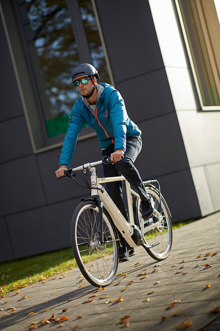 Young man on eBike in urban environment, Munich, Bavaria, Germany