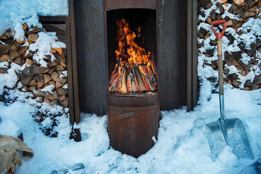 Brennender Holzofen draußen im Winter, Norwegen