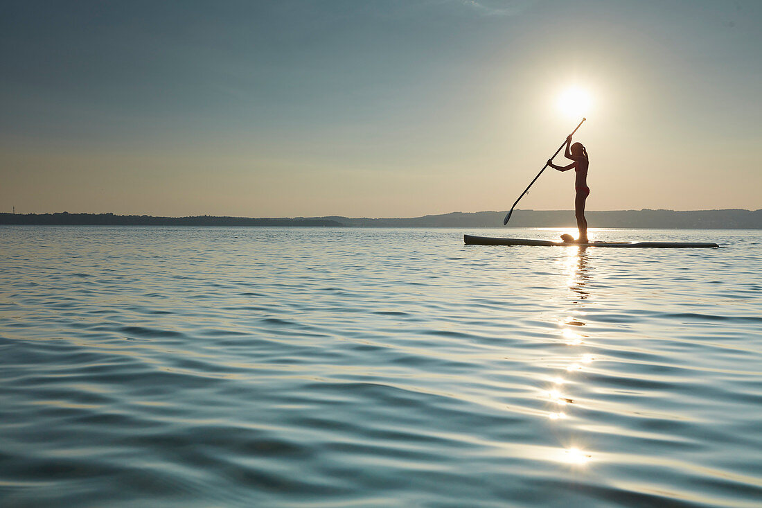 Junge Frau beim Stand Up Paddling auf dem Starnberger See, Bayern, Deutschland
