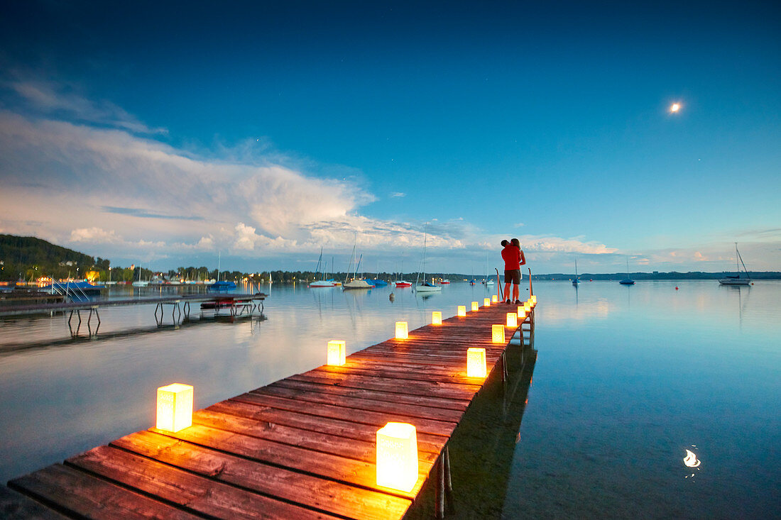 Paar auf einem mit Kerzen beleuchteten Steg, Wörthsee, Bayern, Deutschland