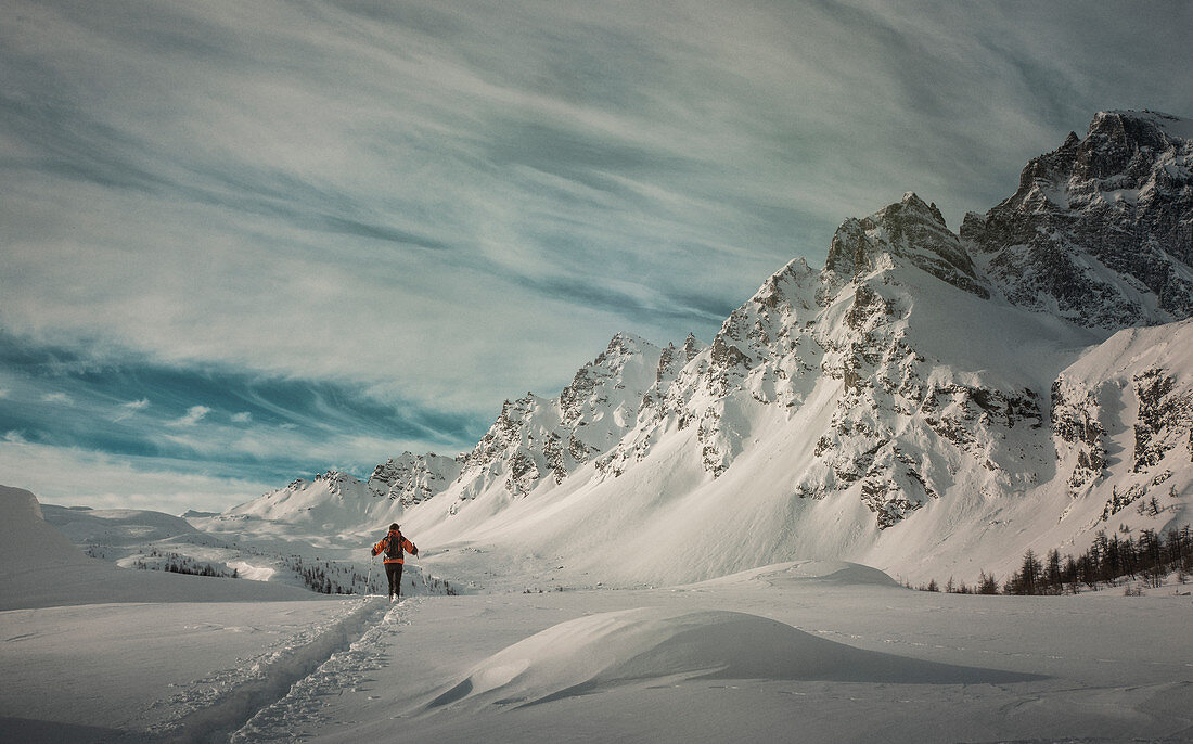 Man hiking through snow by mountain in Alpe Devero, Italy