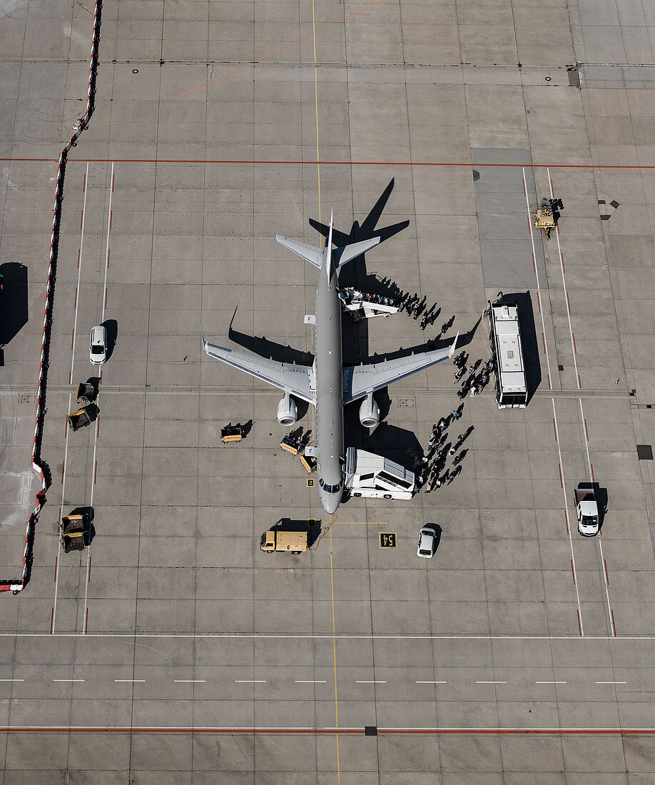 Aerial view of passengers boarding commercial airplane on tarmac at airport