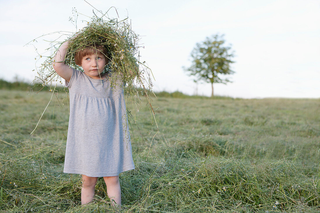 Cute girl playing with grass in rural field