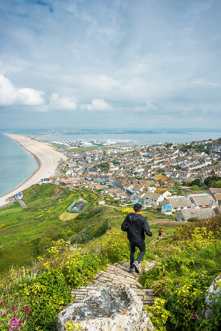 Joggers take the path down to Chesil Beach from Portland heights on the Isle of Portland, Dorset, England, United Kingdom, Europe