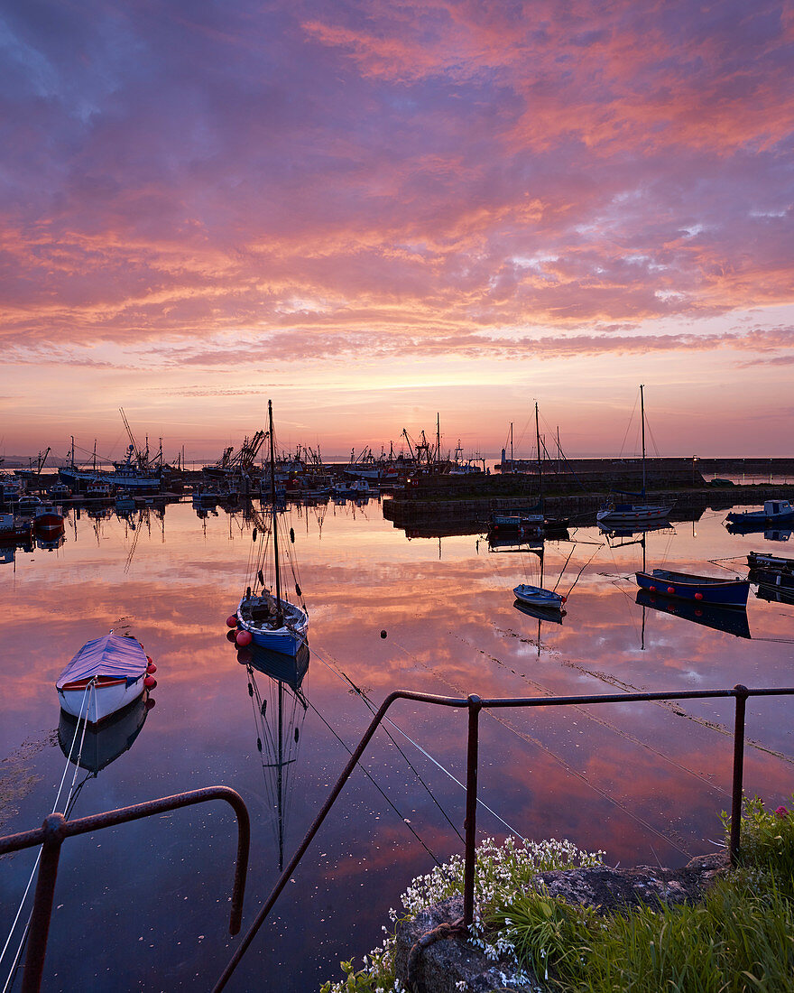 Dawn twilight with underlit clouds, reflections and moored boats in the harbour of the fishing port of Newlyn in Cornwall, England, United Kingdom, Europe