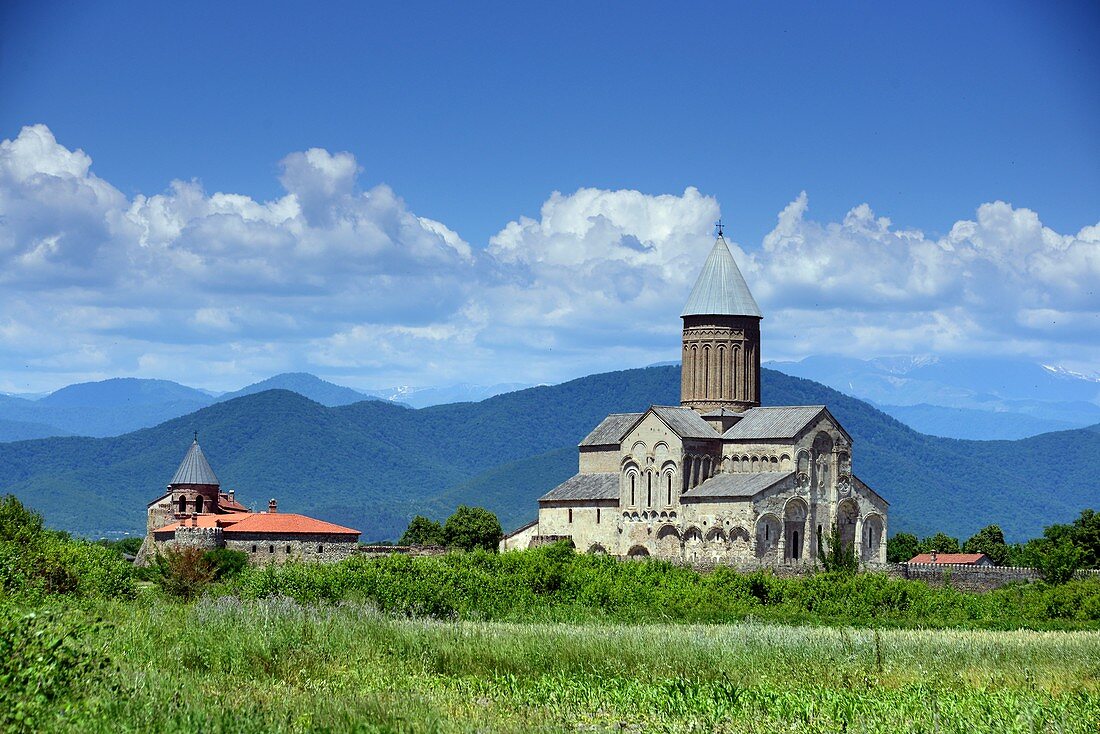 Kloster Alaverdi in grüner Landschaft mit Bergen des Kaukasus im Hintergrund, Kachetien, Georgien