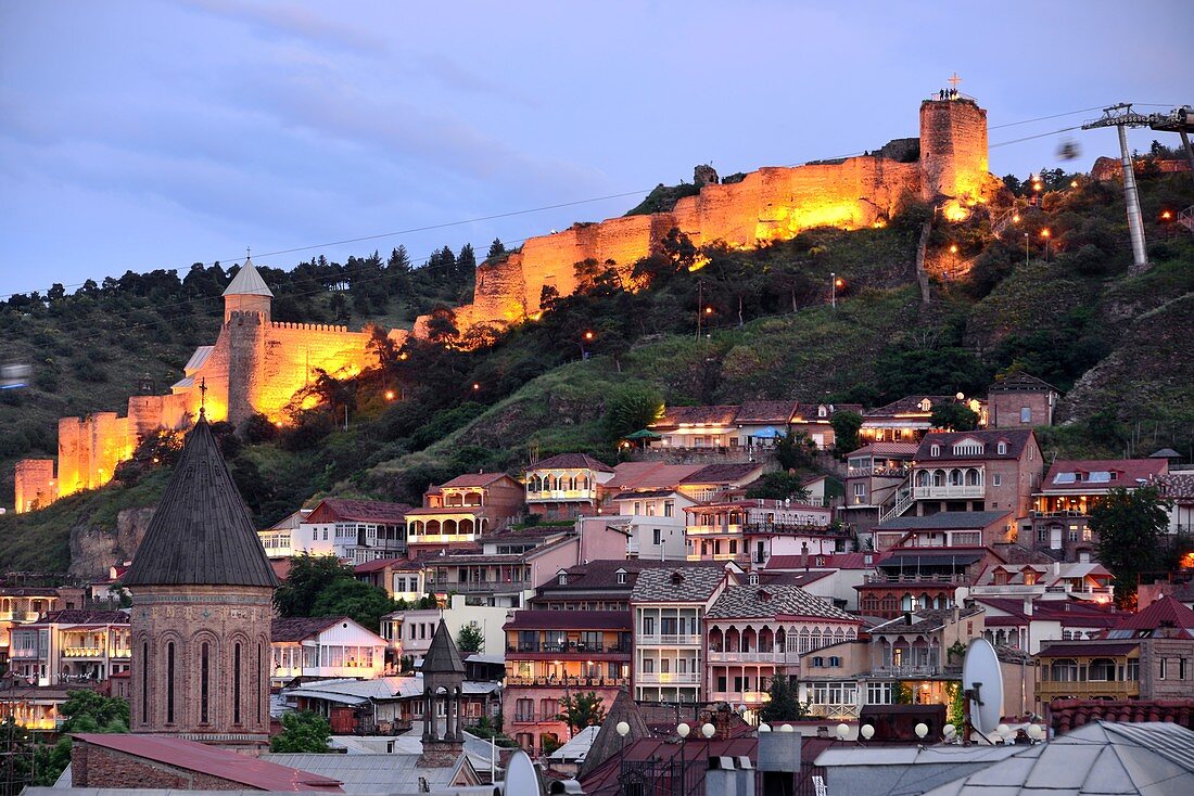 Evening view of the old town and fortress with its houses, churches and part of the city wall, right the cable car station, Tbilisi, Georgia
