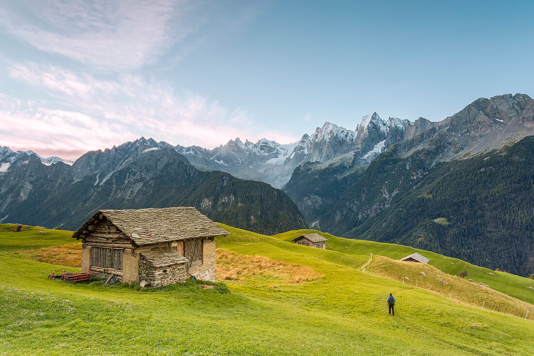 Hiker admiring from an alpine hut the snowy peaks in the background, Tombal, Soglio, Bregaglia Valley, canton of Graub?nden, Switzerland, Europe