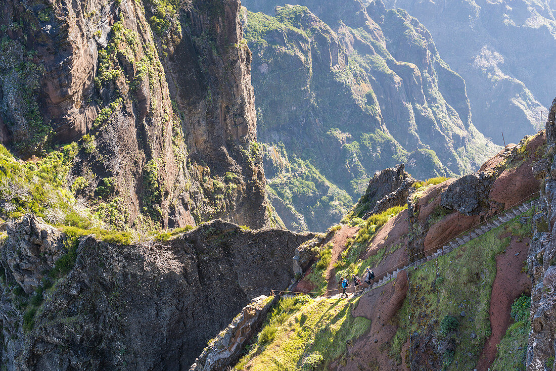 Three people descenging the steps on the trail from Pico Ruivo to Pico do Areeiro. Funchal, Madeira region, Portugal.