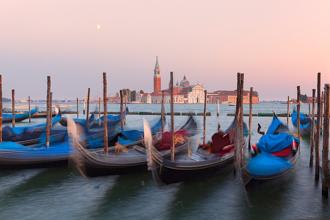 Some traditional venetian gondolas moored at Riva degli Schiavoni with St. George's church on the background, Venice, Veneto, Italy