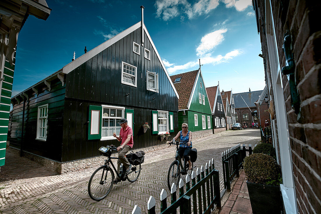 Cyclists and typical houses in Kerkbuurt, Marche island, North Holland, Netherlands