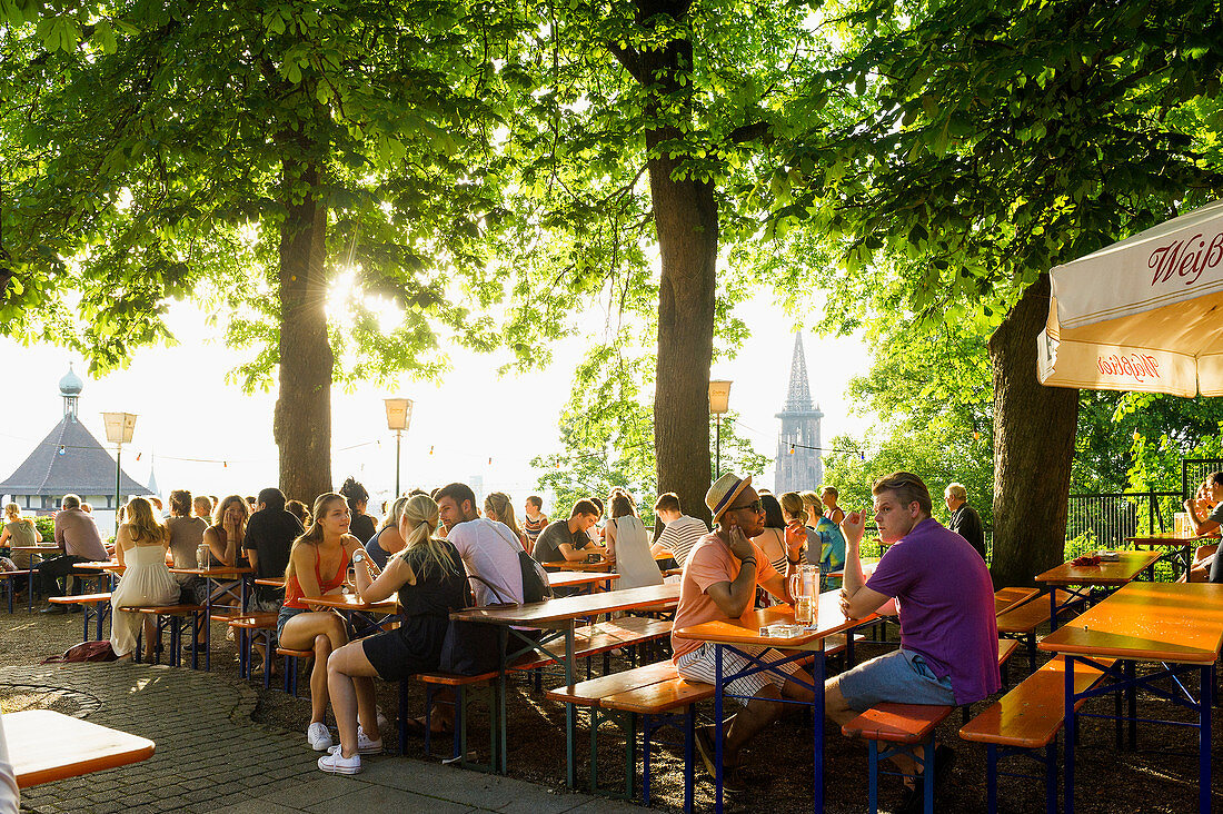 People in the beer garden and Freiburg Minster, sunset, Freiburg im Breisgau, Black Forest, Baden-Wurttemberg, Germany