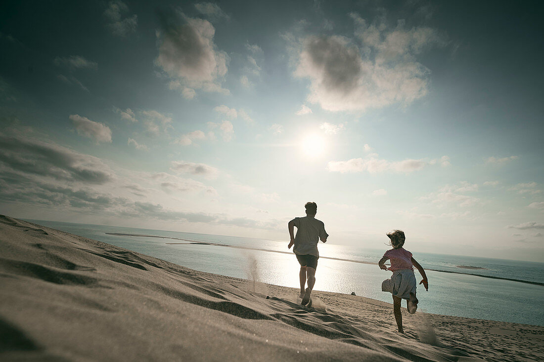 Boy and girl are running down the dune, Dune d'Arcachon, French Atlantic Coast, Aquitaine, France