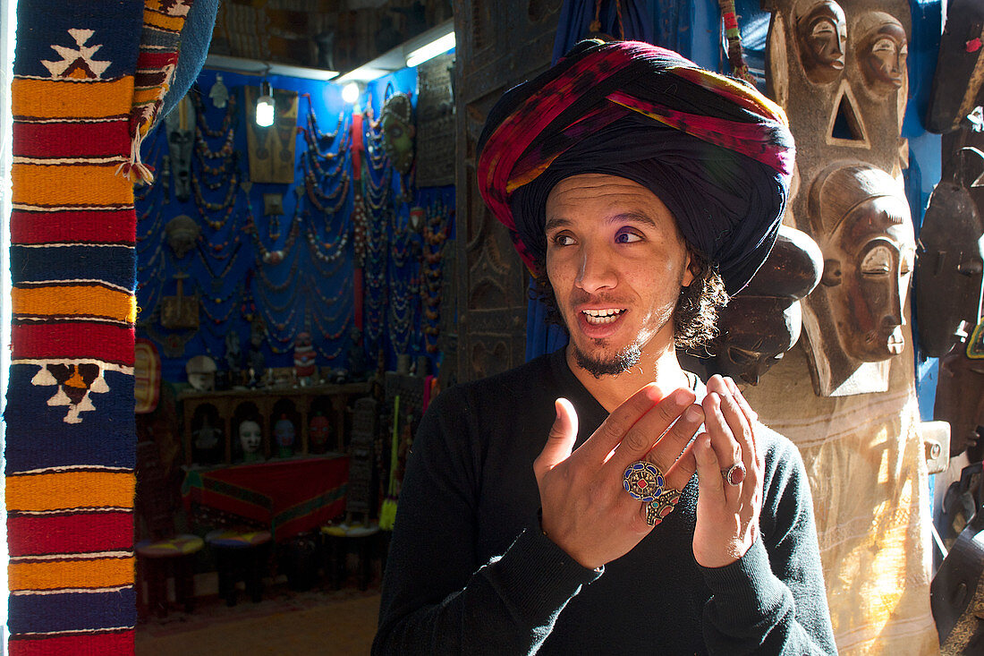 Junger Mann mit Turban, Marokkaner, Berber, steht vor seinem Geschäft in Essaouira, Atlantikküste, Marokko