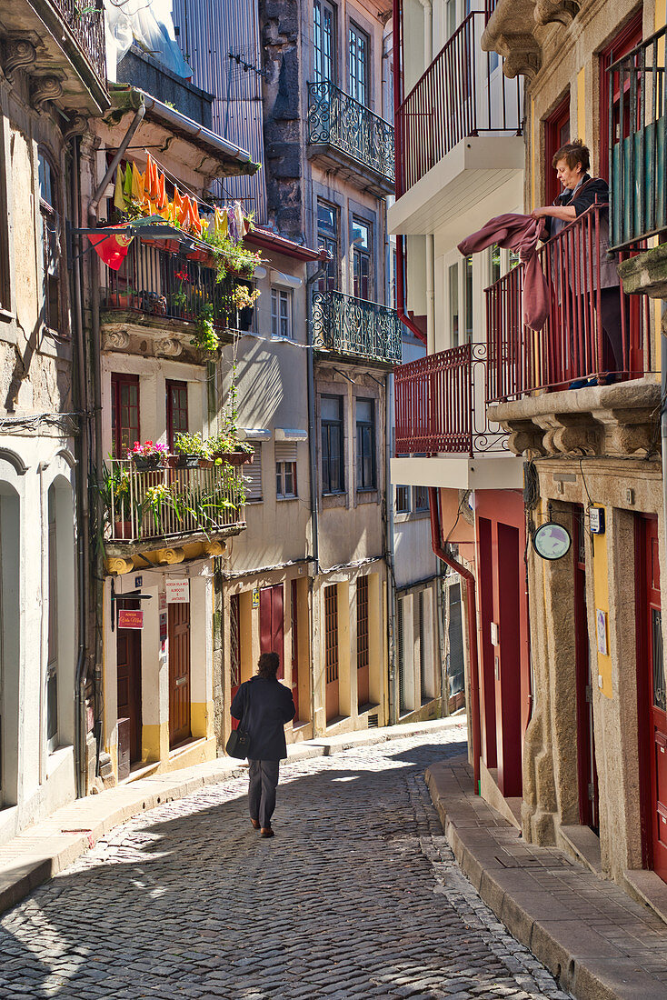 Gasse vom Torre de Clerigo zum Cais da Ribeira mit einer Person und einer Frau auf einem Balkon Porto, Portugal
