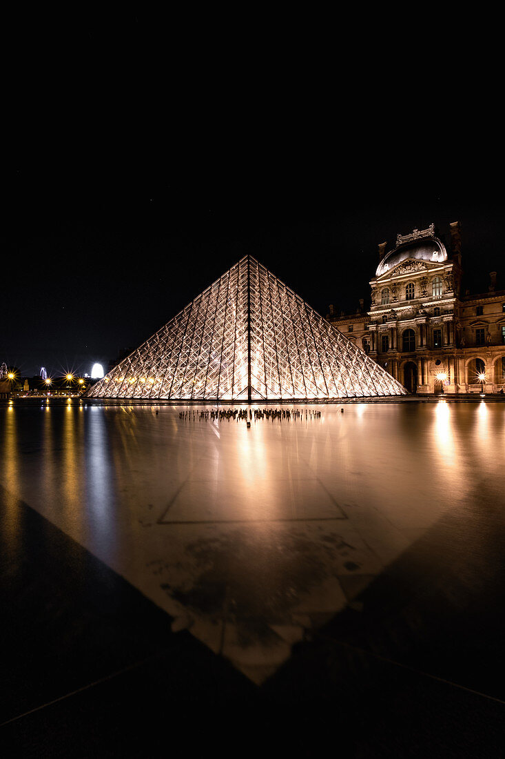 Illuminated pyramid in the Louvre at night, light reflections in the fountain basin in front of the glass pyramid, Île-de-France, Paris, France