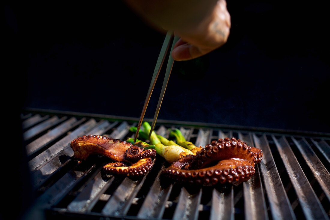 Chef with chopsticks grilling octopus