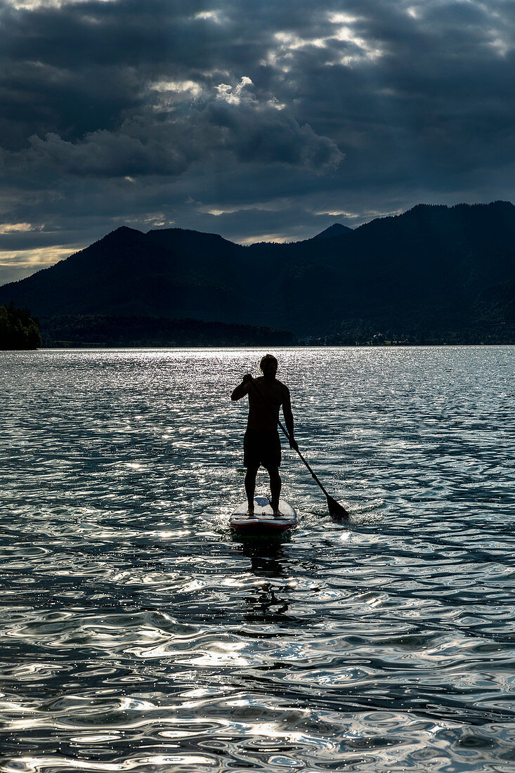 Silhouette man paddleboarding on sunny, idyllic lake, Walchensee, Bavaria, Germany