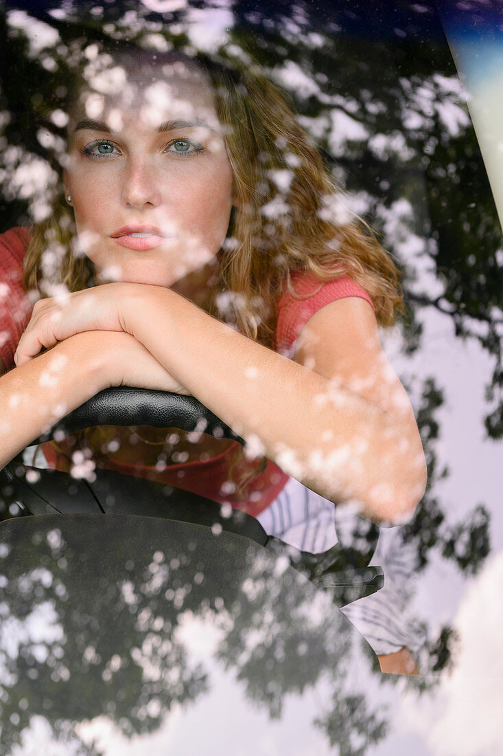Blick durch die Windschutzscheibe auf junge Frau im Auto