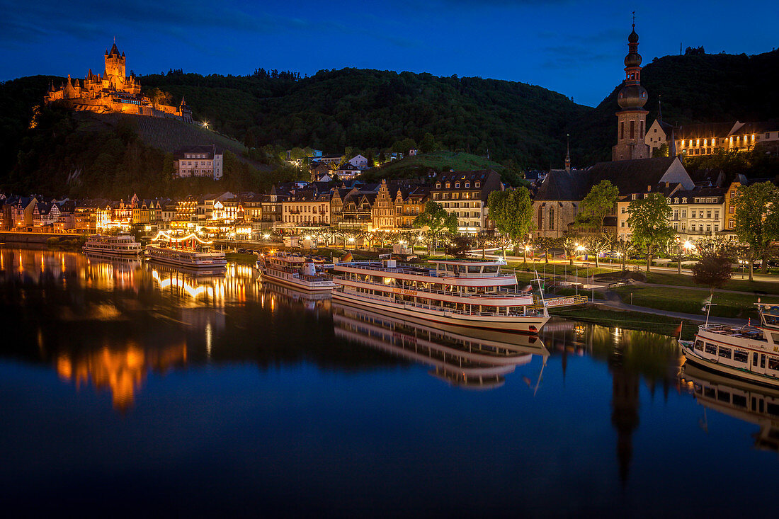 Blick über Fluss auf Stadt und Reichsburg Cochem bei Sonnenuntergang in Cochem, Deutschland