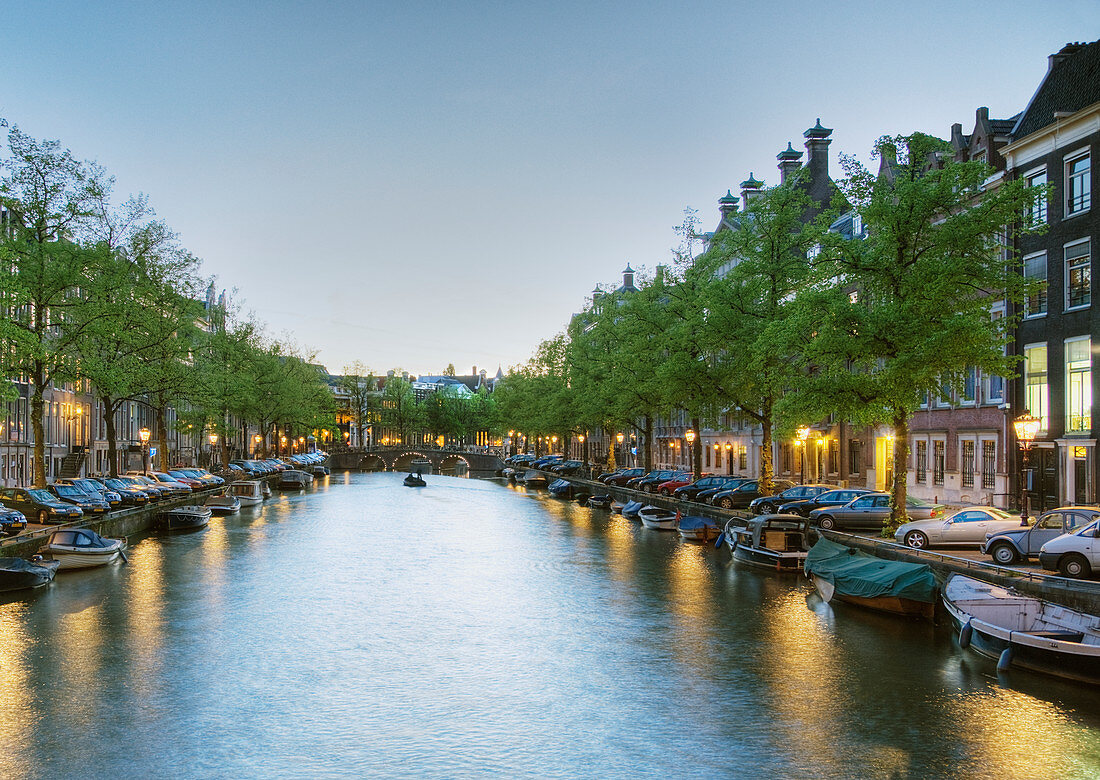 Boote auf einem baumgesäumten Kanal bei Dämmerung, Amsterdam, Niederlande