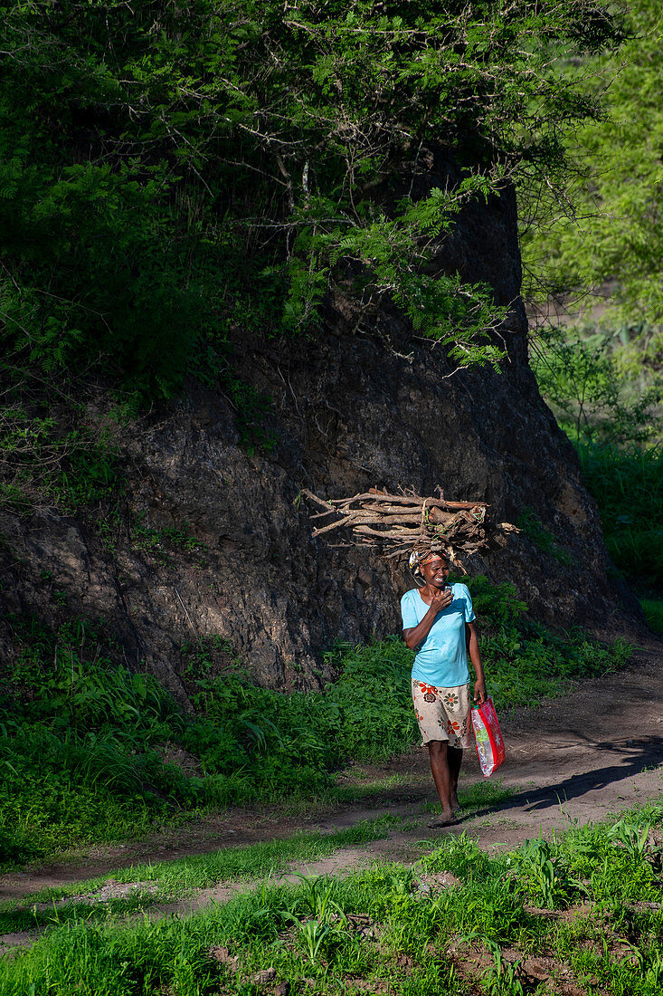 Junge Frau trägt Brennholz auf ihrem Kopf, Insel Santiago, Kap Verde