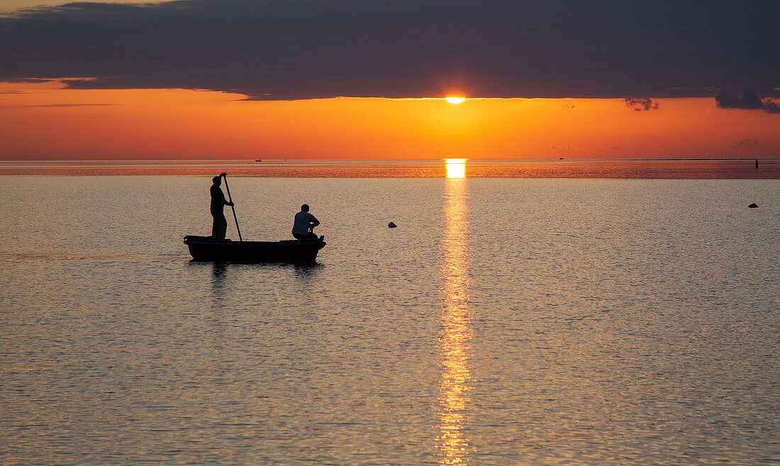 Sonnenuntergang in Marsala, Sizilien mit einem Fischerboot und zwei Fischern im Vordergrund