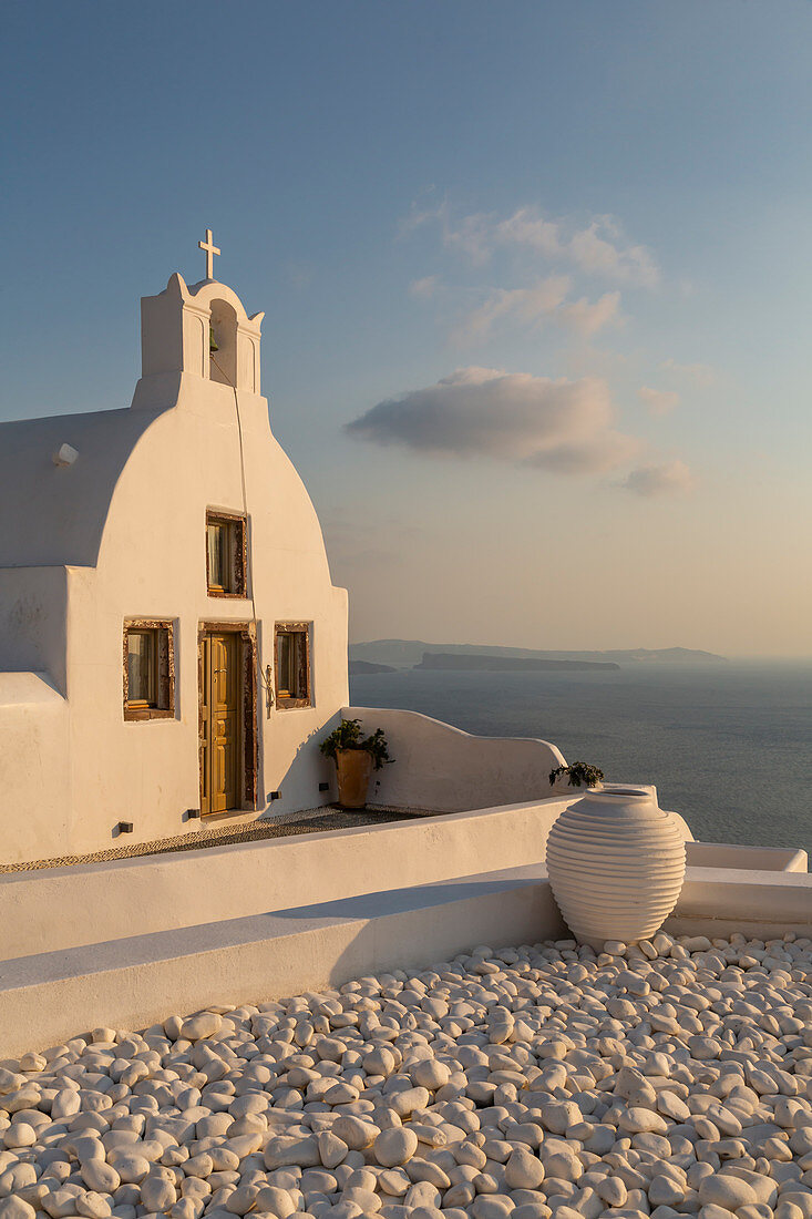 Blick auf kleine traditionelle, weiß getünchte Kirche bei Sonnenuntergang in Oia, Santorini, Kykladen, Ägäische Inseln, griechische Inseln, Griechenland, Europa