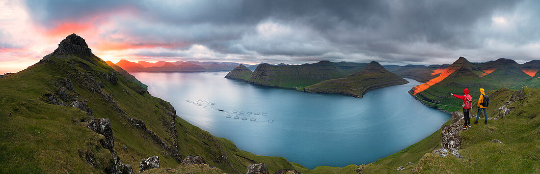 Panoramic of hikers on cliffs looking to the fjords, Funningur, Eysturoy island, Faroe Islands, Denmark, Europe