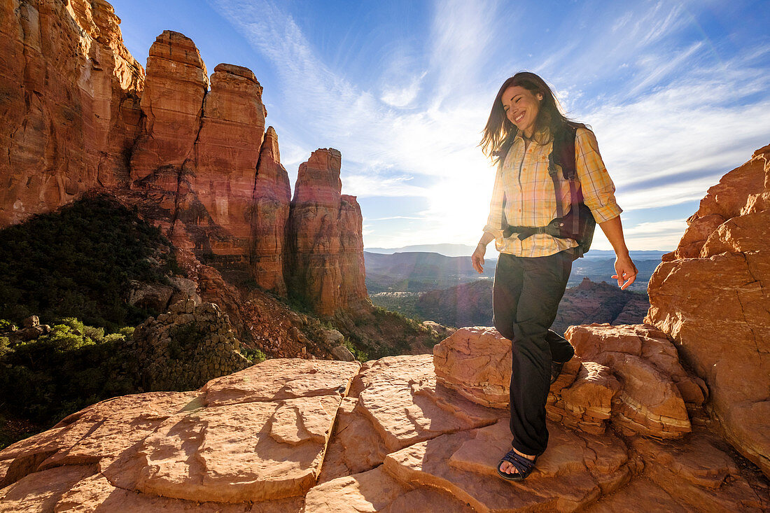 Female hiker walking down rocks at Cathedral Rock with setting sun in background, Arizona, USA