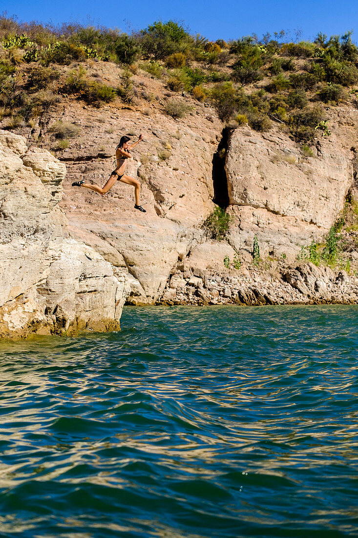 Mädchen springt von der Klippe in Roosevelt Lake, Arizona.