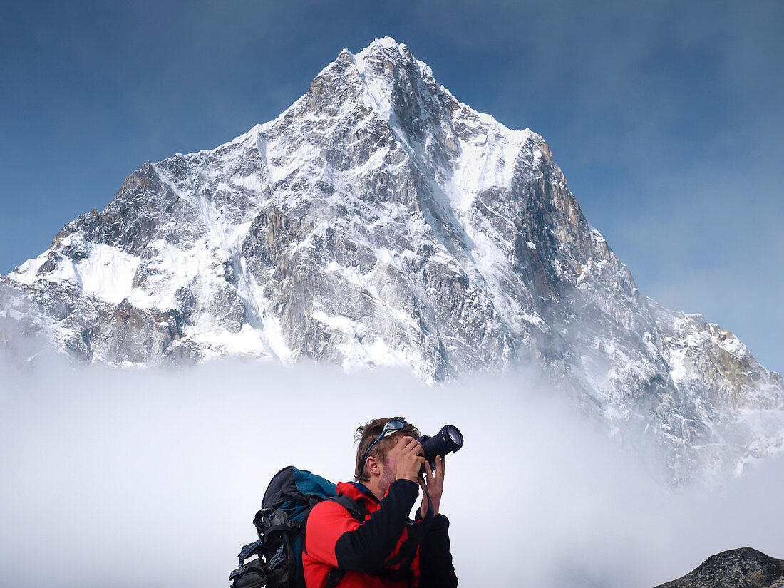 Trekker is taking picture while mount Cholatse is rising above clouds, Khumbu, Nepal