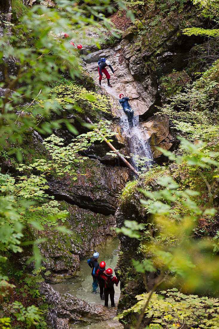 Canyoning in narrow gorge filled with rapids, pools and waterfalls in Soca valley near Bovec, Slovenia