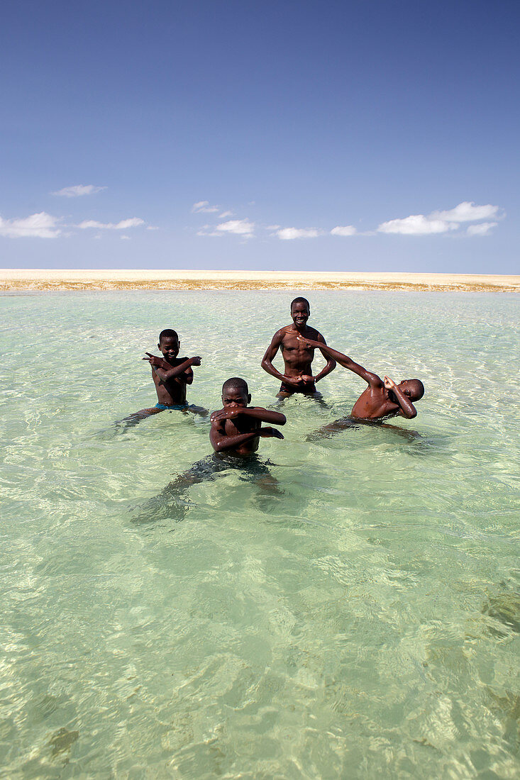 Four boys posing together in coastal water, Mozambique