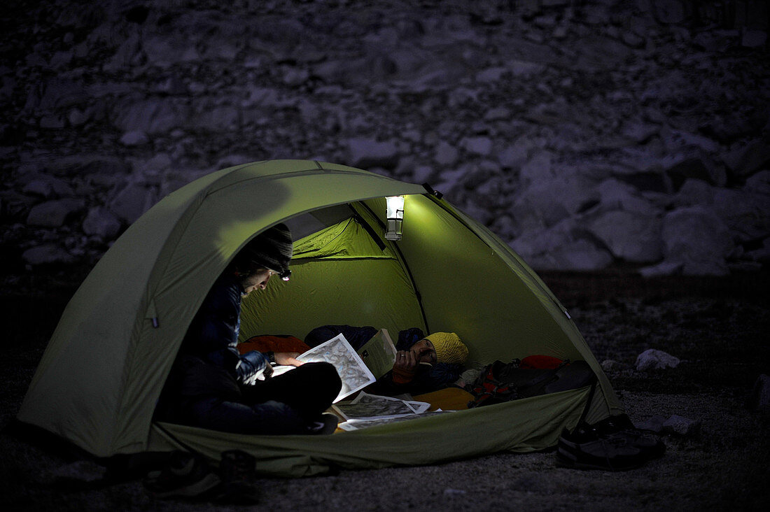 Backpackers look over the map by headlamp in their tent at camp at Brown Bear Lake on a two-week trek of the Sierra High Route in the John Muir Wilderness in California. The 200-mile route roughly parallels the popular John Muir Trail through the Sierra Nevada Range of California from Kings Canyon National Park to Yosemite National Park. 