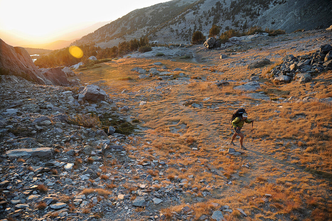 Backpacker hiking to Deer Lakes on Mammoth Crest trail at sunset, California, USA