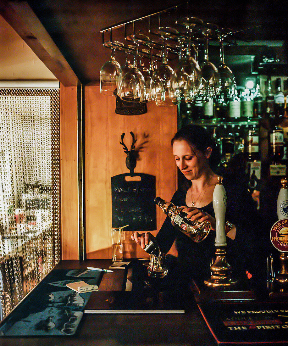 Bartender pouring scotch at local bar in Broadford, Isle of Skye, Scotland, UK