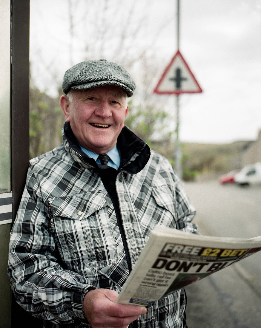 Schotte steht am Straßenrand mit Zeitung, Bettyhill, Farr, Schottland, UK