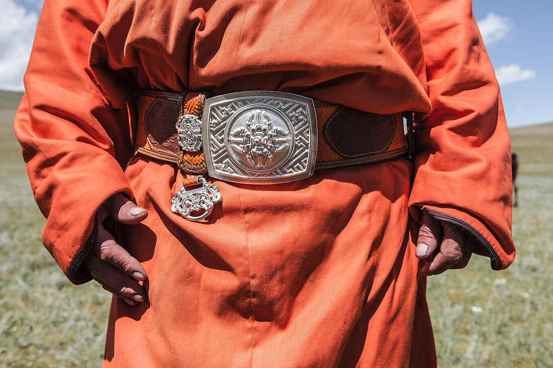 Mid section of mongolian man wearing deel, national dress of Mongolia, tied with leather belt with big silver buckle, Naadam Festival, Bunkhan Valley, Bulgam, Mongolia