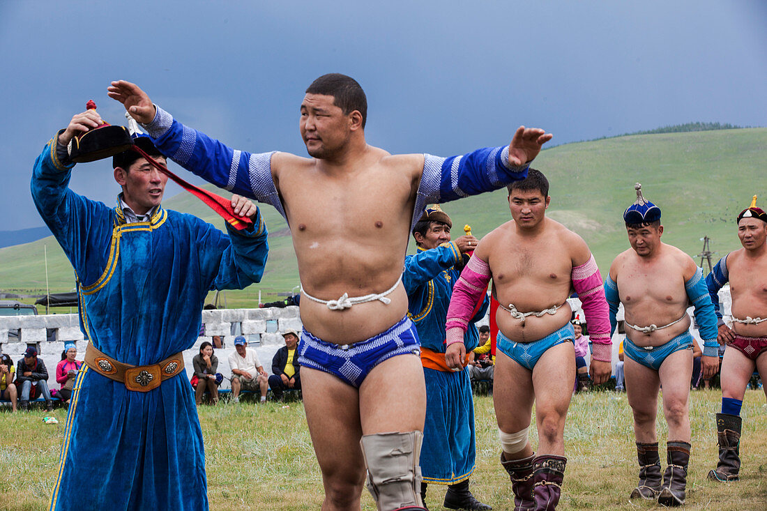 The wrestlers displaying their strong physique in a warm-up Eagle Dance whilst their coaches announce their heroic deeds. Then over a dozen pairs will fight simultaneously in front of an excited audience. The round ends when one of the contestants touches the ground with their knee or elbow. Annual Naadam Festival in Tsetserleg, Arkhangai Province, Mongolia