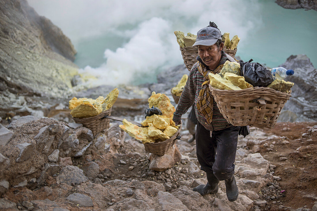 Sulfur miner carrying heavy load of Sulphur at top of Kawah Ijen Volcano, Java, Indonesia